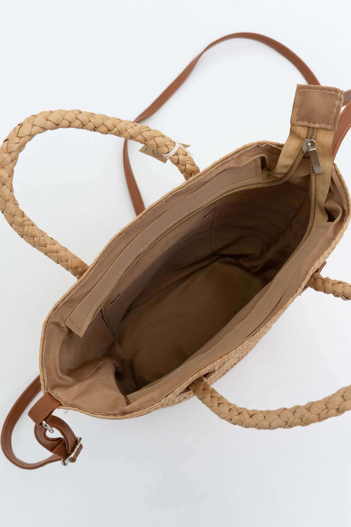 Top view of spacious interior and zip pocket in woven straw tote bag