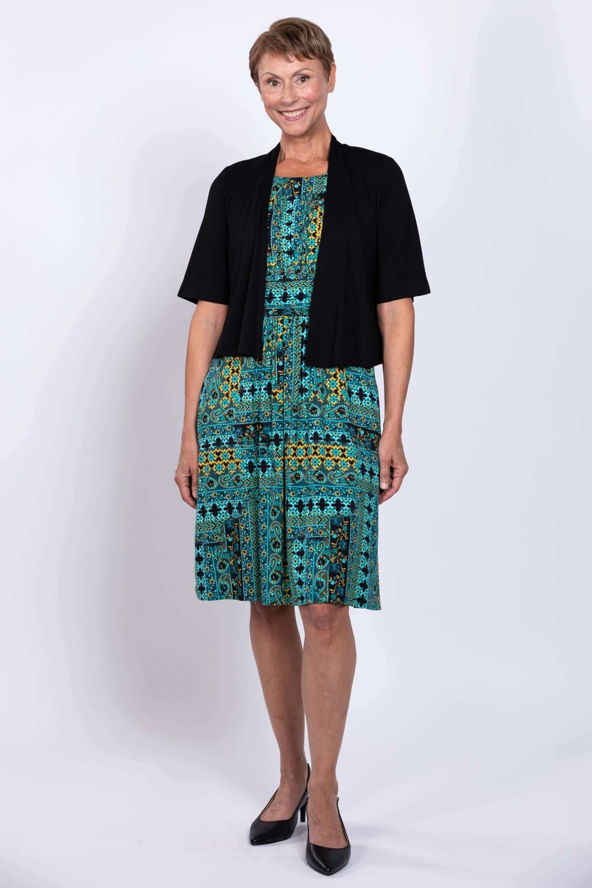 Woman in turquoise mosaic dress with black short-sleeve cover-up, front view