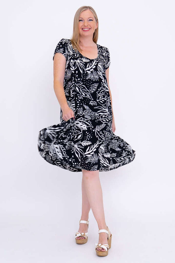 Woman twirling in a black and white flowy dress with leafy pattern