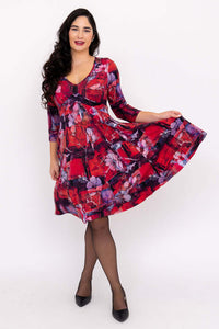Woman twirling in a crimson floral V-neck fit and flare dress with 3/4 sleeves
