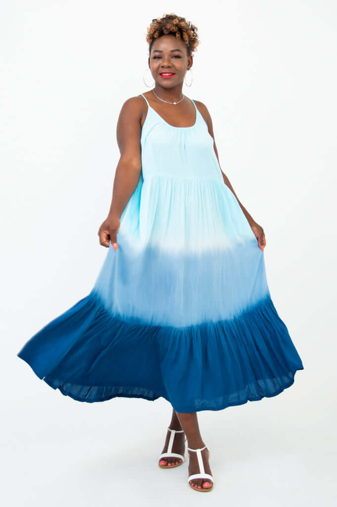 Woman twirling in a blue ombre maxi dress with a tiered hem