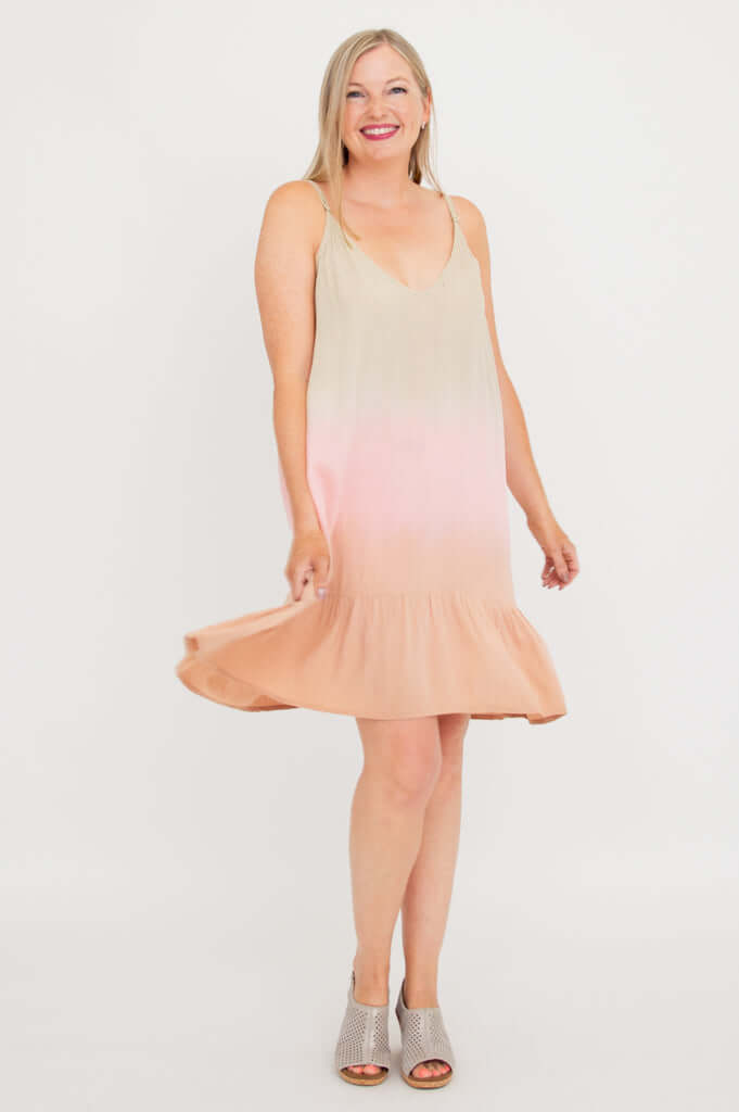 Woman twirling in sleeveless ombre dress with adjustable straps and flounce hem