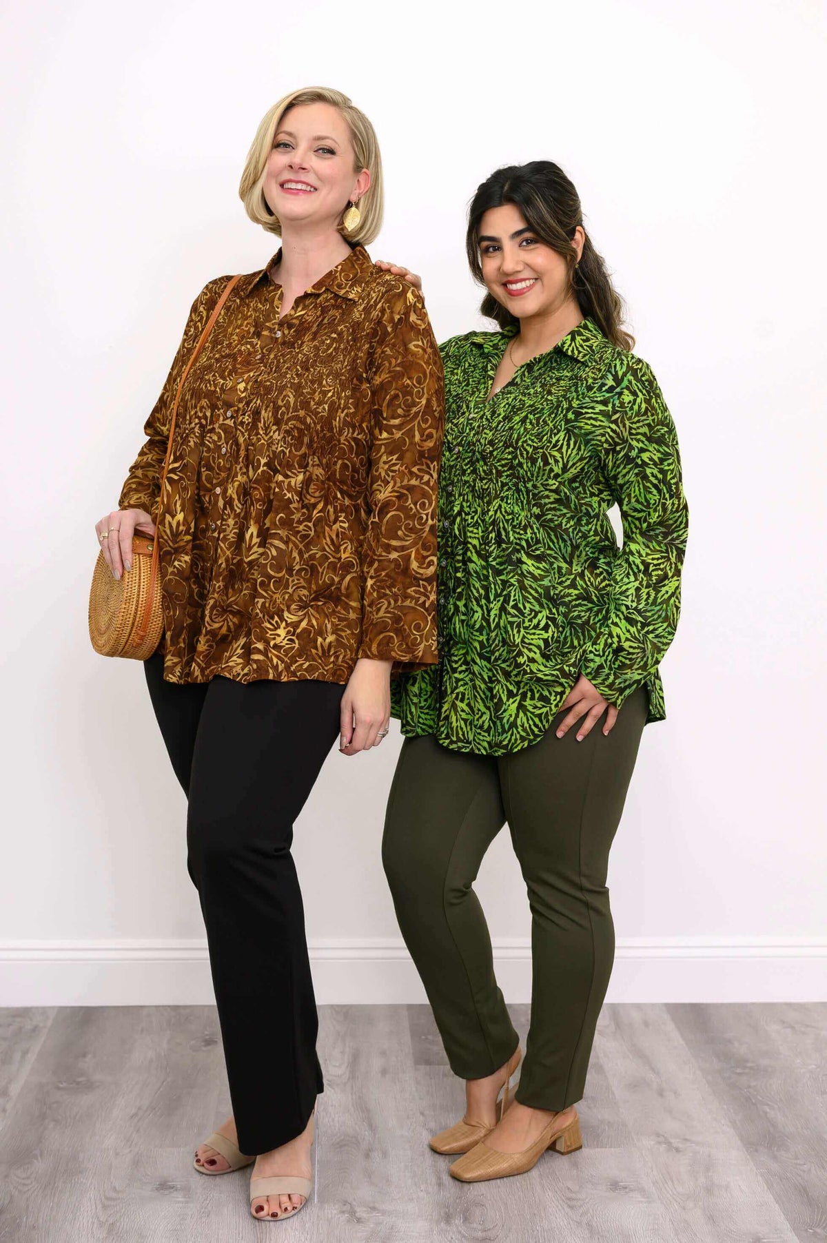 Two models in Cindy shirts, one in green leaf print and one in brown, standing side by side