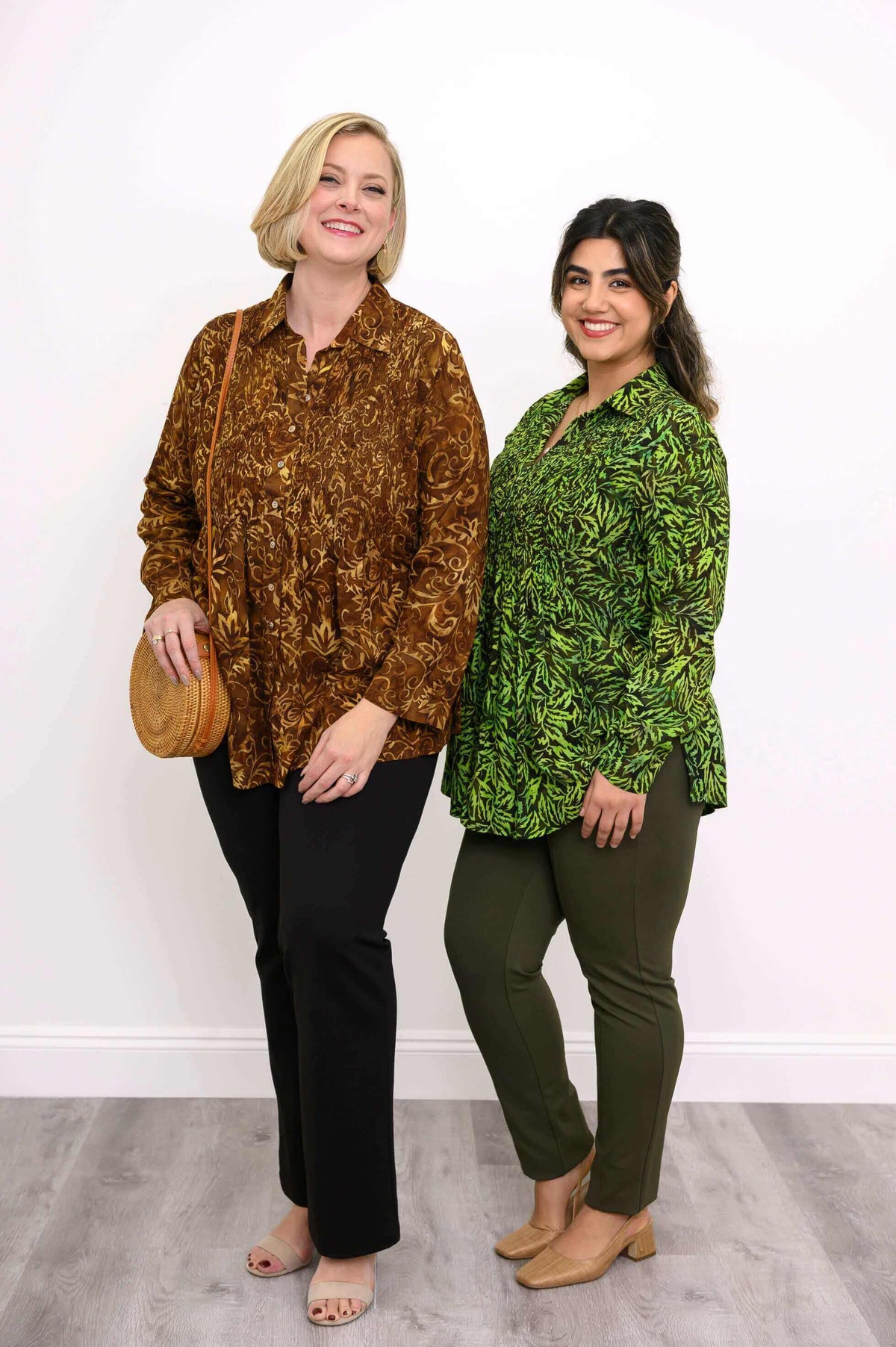 Two models in long sleeve smocked shirts, one in brown floral and one in green print