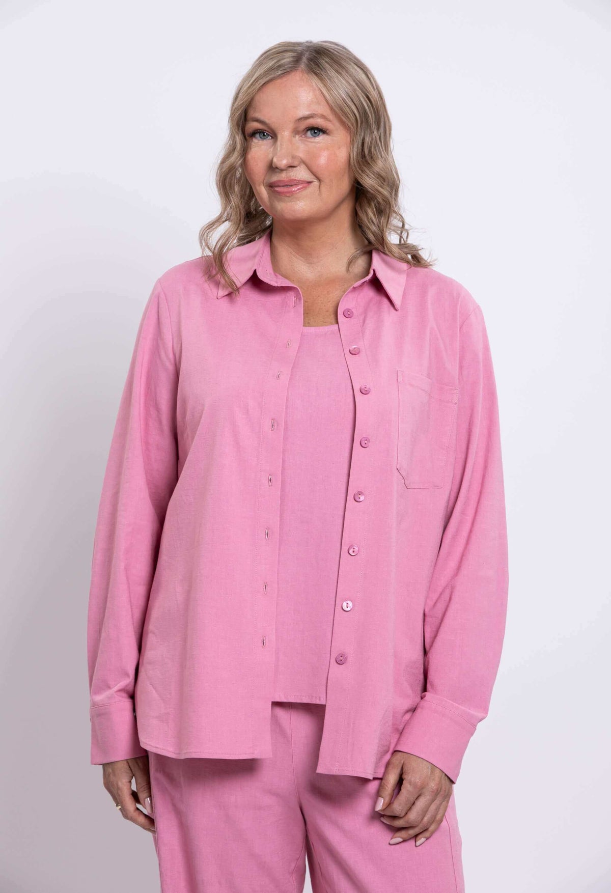 Woman in a pink linen shirt with breast pocket, front view upper body and hand in pocket