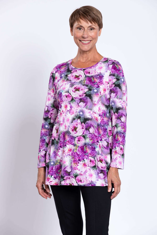 Woman wearing a vibrant purple floral long sleeve tunic with black pants