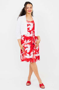 Model wearing a red and white floral pleated dress with white knit bolero