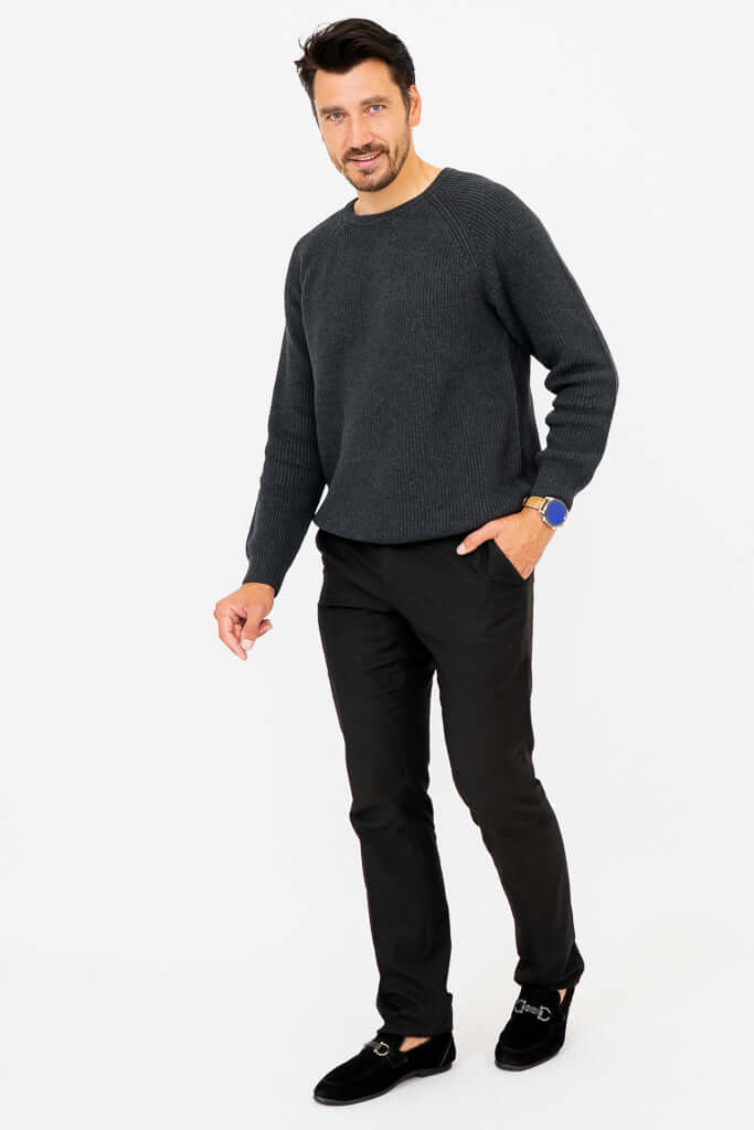 Man walking in charcoal sweater and black pants with a smile