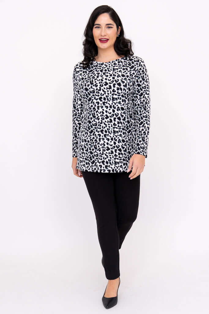 Woman walking forward in a black and white animal print tunic top and black trousers