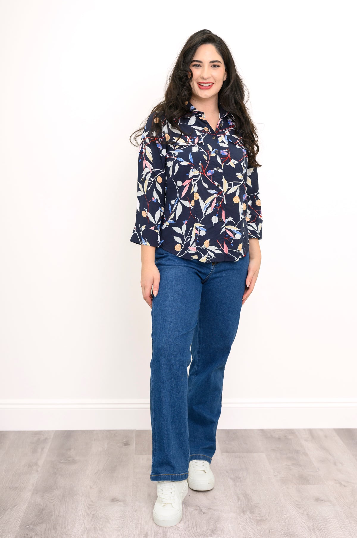 front view of woman wearing navy blue blouse with multicolor floral print on a white background