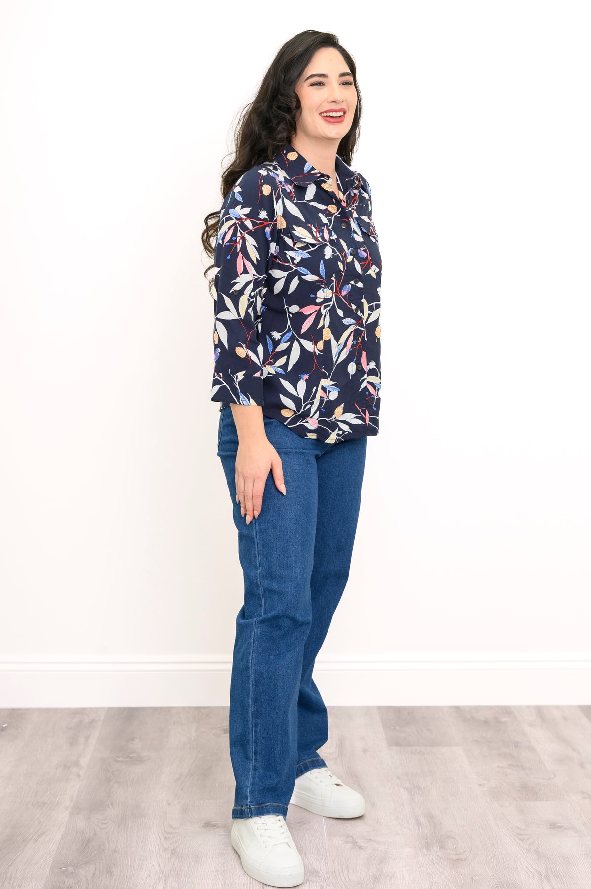 side view of woman wearing navy blue blouse with multicolor floral print on a white background