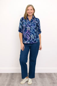 Front view of woman wearing a blue patterned blouse and jeans against a white background