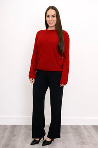 full body front view of woman dressed in long-sleeve red sweater and straight leg black pants