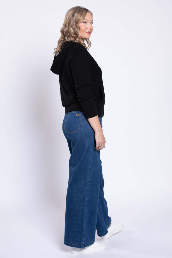 Model in wide leg denim jeans and black hoodie, side view