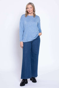 Model wearing wide leg medium wash denim jeans and blue sweater, front view