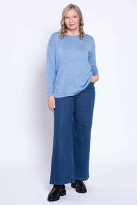 Model in wide leg denim jeans and blue sweater, relaxed pose, front view