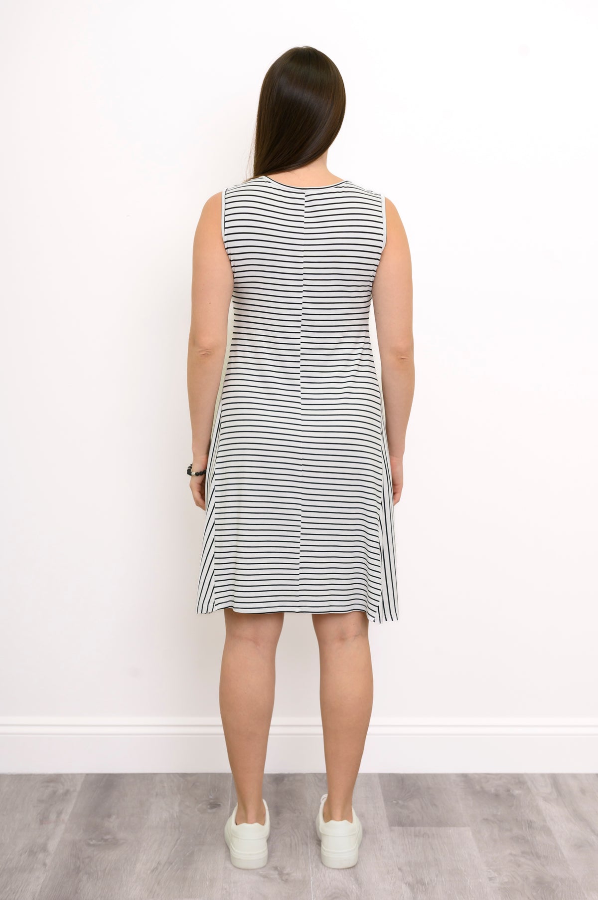 Back view of a woman wearing the Willow Dress in white and black small stripe bamboo fabric showing the knee-length hem.