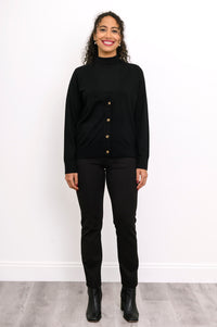 Full length view of a woman wearing a black merino wool v-neck cardigan sweater and black pants.