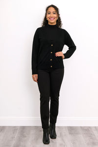 Front view of a woman wearing a black merino wool button down cardigan layered over black pants.