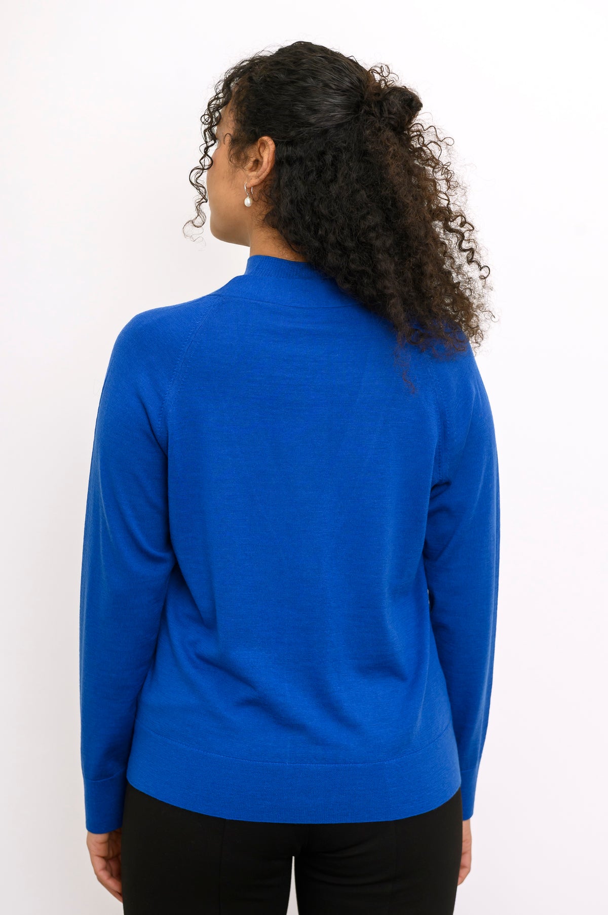 Rear view of a long sleeve cobalt blue fine wool knit sweater showing clean back fit and ribbed hem.
