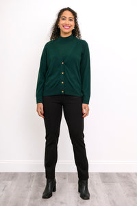 Full length shot of a woman in a deep green fine knit wool cardigan sweater styled with black boots.