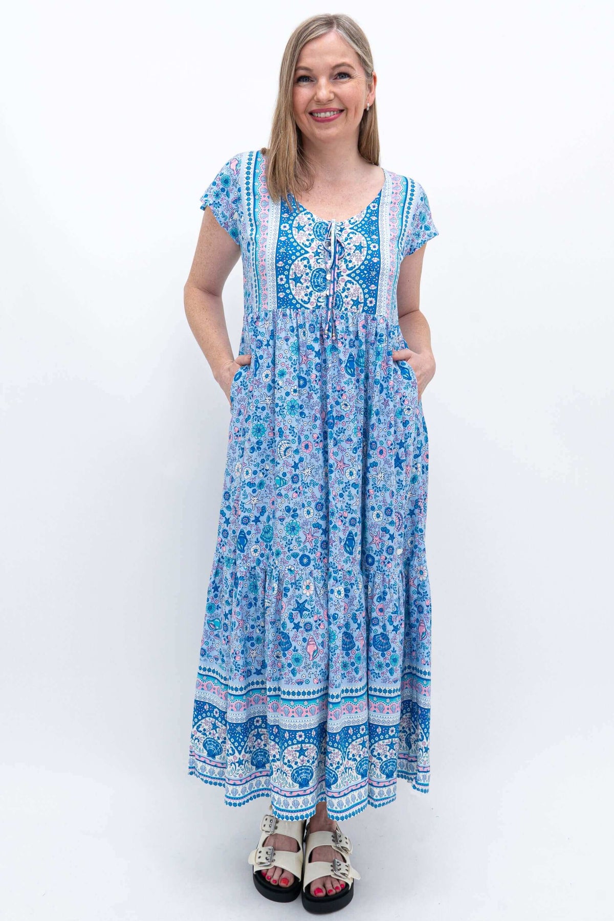 Woman displaying practical pockets on blue Sharpie Dress with front buttons