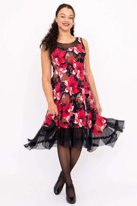 Woman wearing sleeveless red floral dress with mesh hem and empire waist