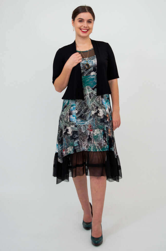Woman in a sleeveless printed dress with mesh hem and short black jacket