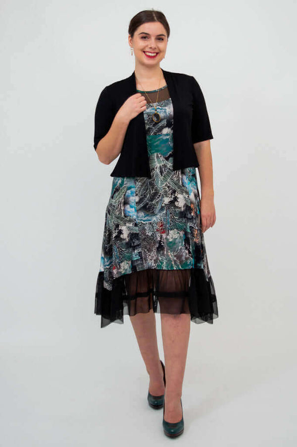 Woman in a sleeveless printed dress with mesh hem and short black jacket