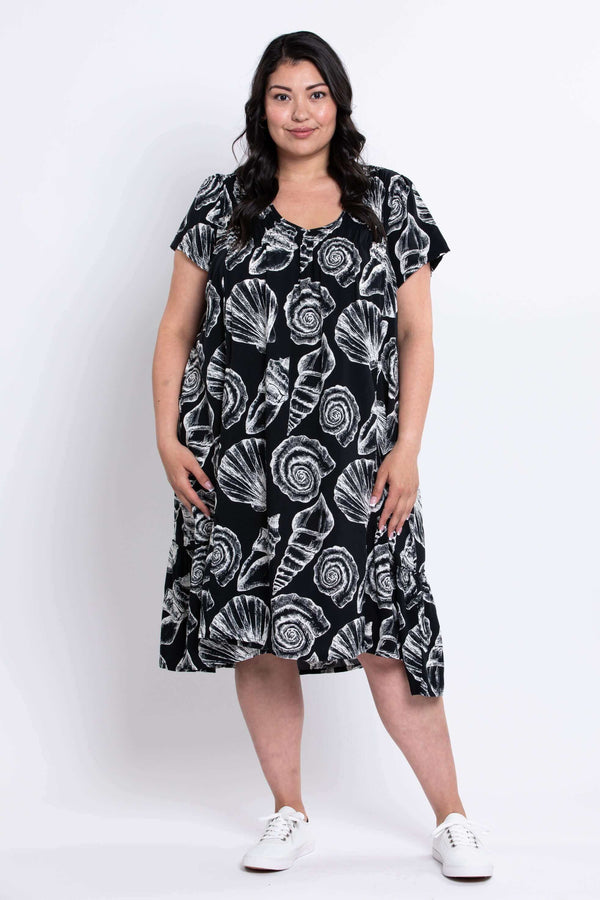 Woman wearing a black flowy dress with white shell print standing facing forward