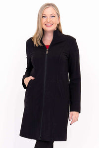 Woman in black princess seam coat smiling, hand in pocket, close-up view