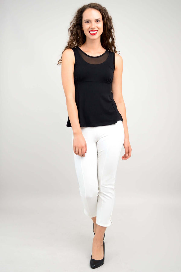 Woman in black tank top with mesh panel, walking forward, wearing white pants