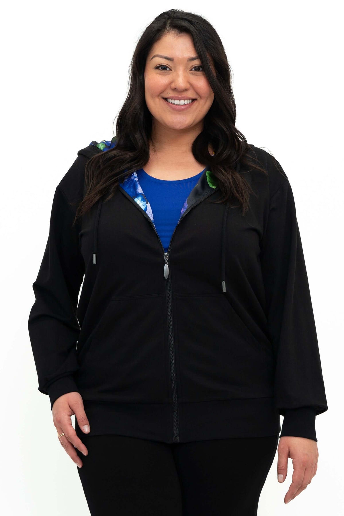 Woman wearing black zip hoody with a hint of colorful floral lining showing