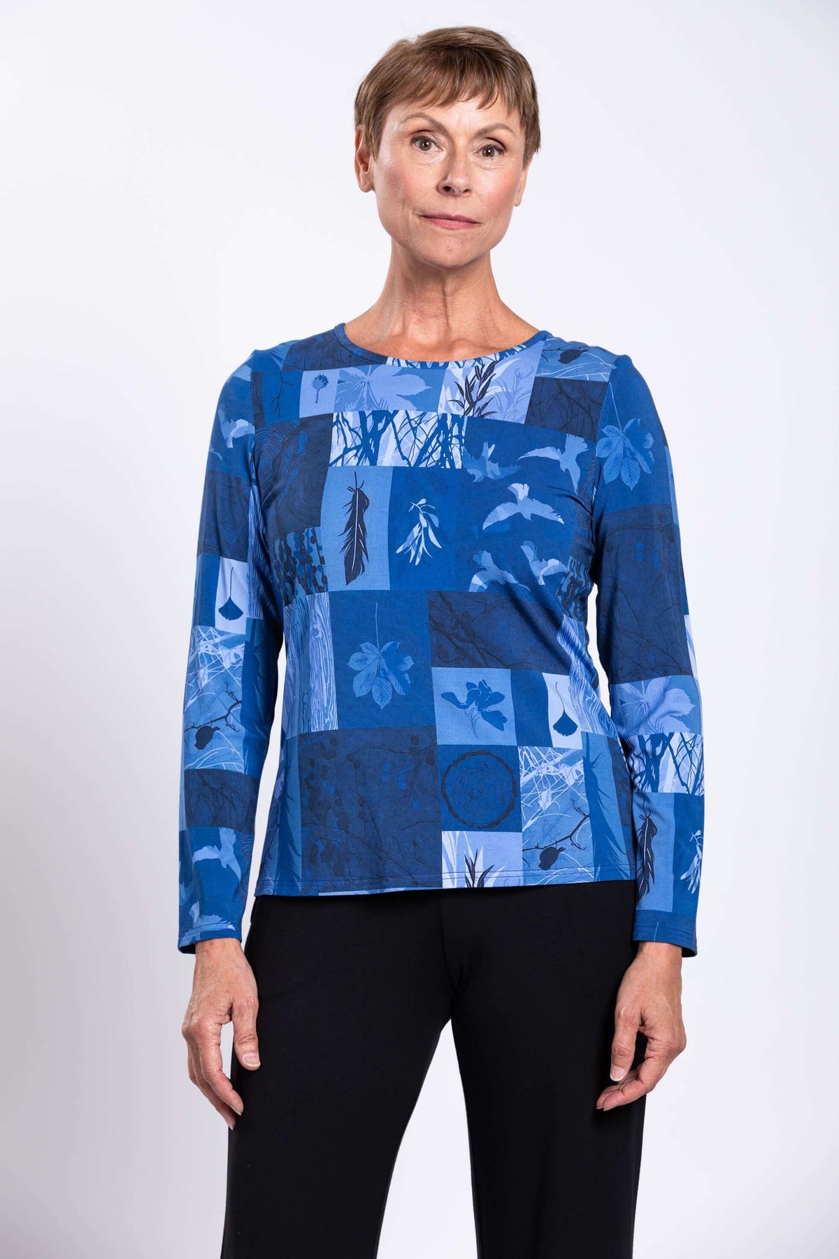 Woman wearing a blue botanical print long sleeve tee with black pants, front view