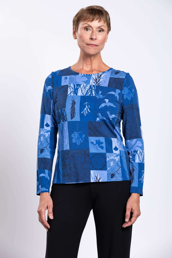 Woman wearing a blue botanical print long sleeve tee with black pants, front view