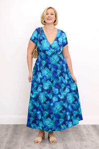 Woman smiling in a blue floral bamboo dress, hands resting on skirt pockets