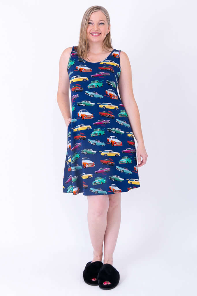 Woman wearing sleeveless dress with colorful classic car print, hands in pockets