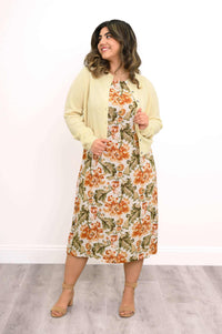 Woman in floral dress and buttoned cardigan, looking to side, smiling