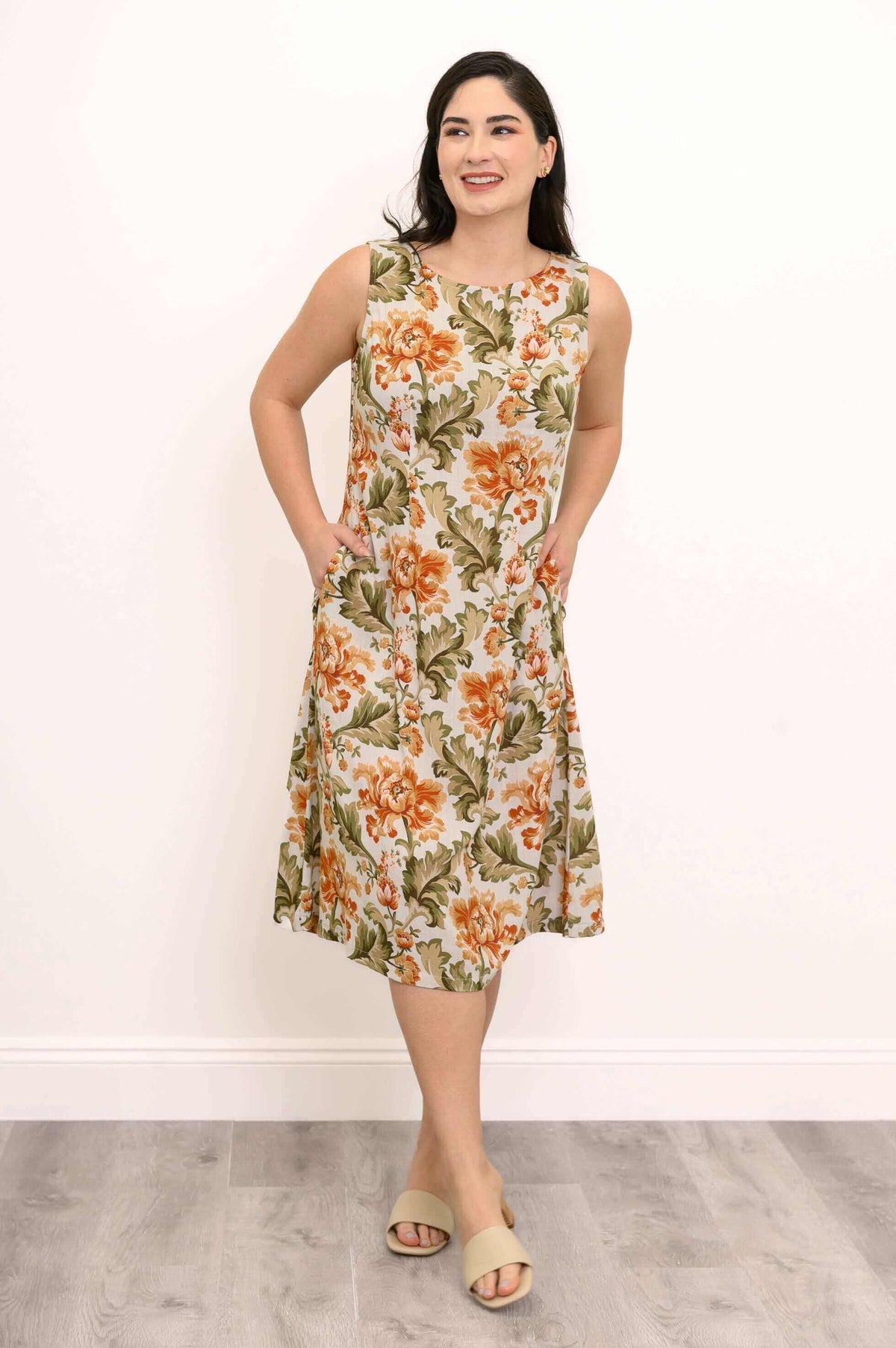 Woman in floral midi dress, hands in pockets, smiling