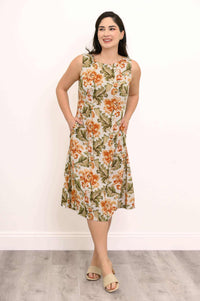 Woman in floral midi dress, hands in pockets, smiling
