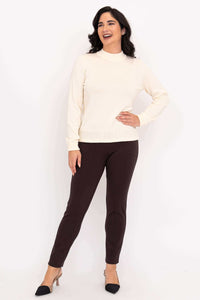 Woman smiling in ivory mock neck sweater and brown pants