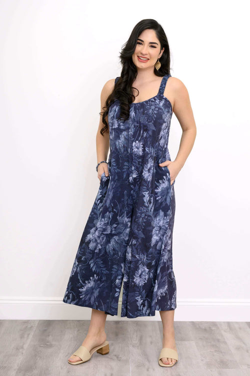 Woman wearing a navy floral jumpsuit with sweetheart neckline and pockets, full body view