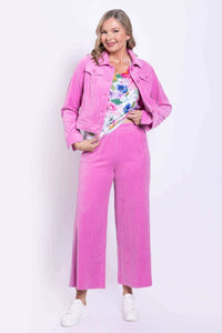 Woman wearing a pink corduroy jacket and matching wide-leg pink pants with floral top
