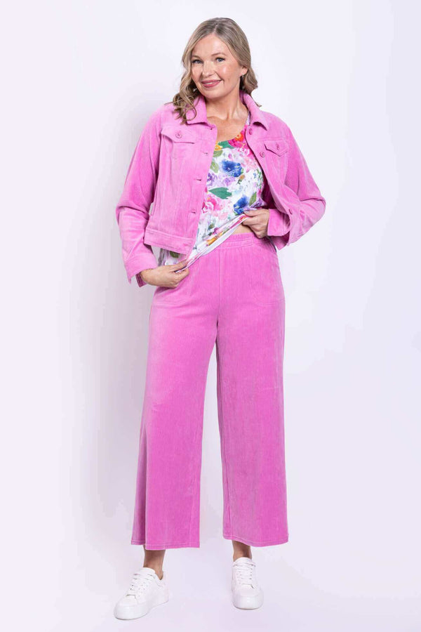 Woman wearing a pink corduroy jacket and matching wide-leg pink pants with floral top