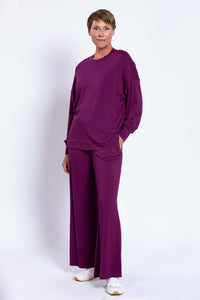 Woman with hand in pocket wearing plum bamboo crew neck top and pants set