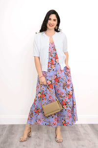 Woman styled in a purple floral jumpsuit with a light cardigan and tan handbag