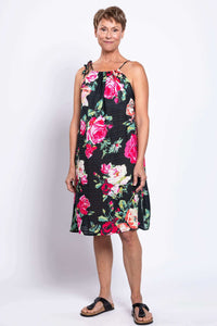 Smiling woman facing camera in loose fit floral summer dress with tie strap