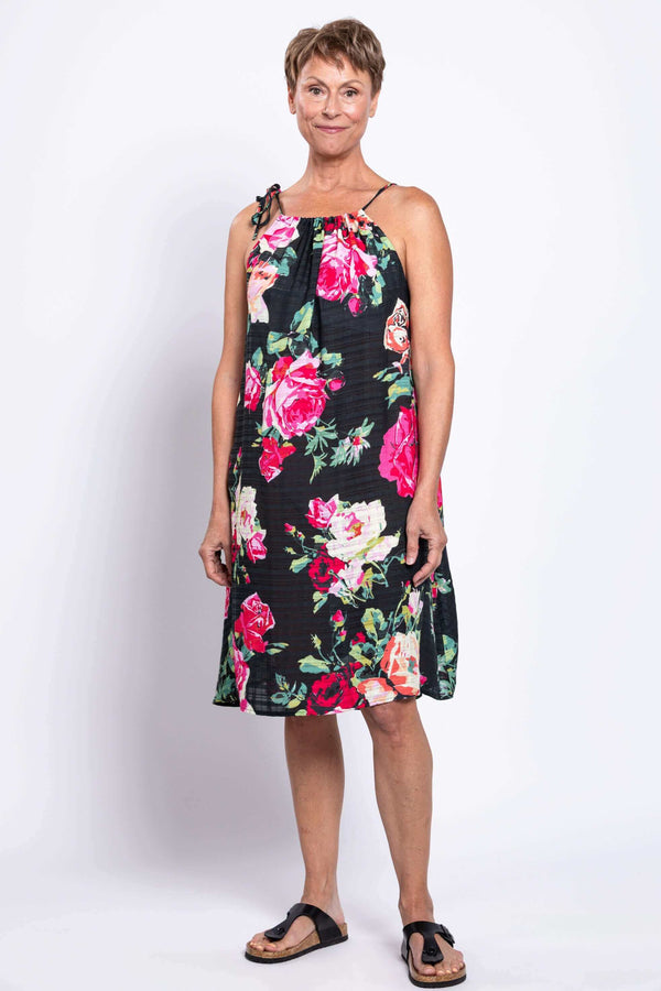 Smiling woman facing camera in loose fit floral summer dress with tie strap