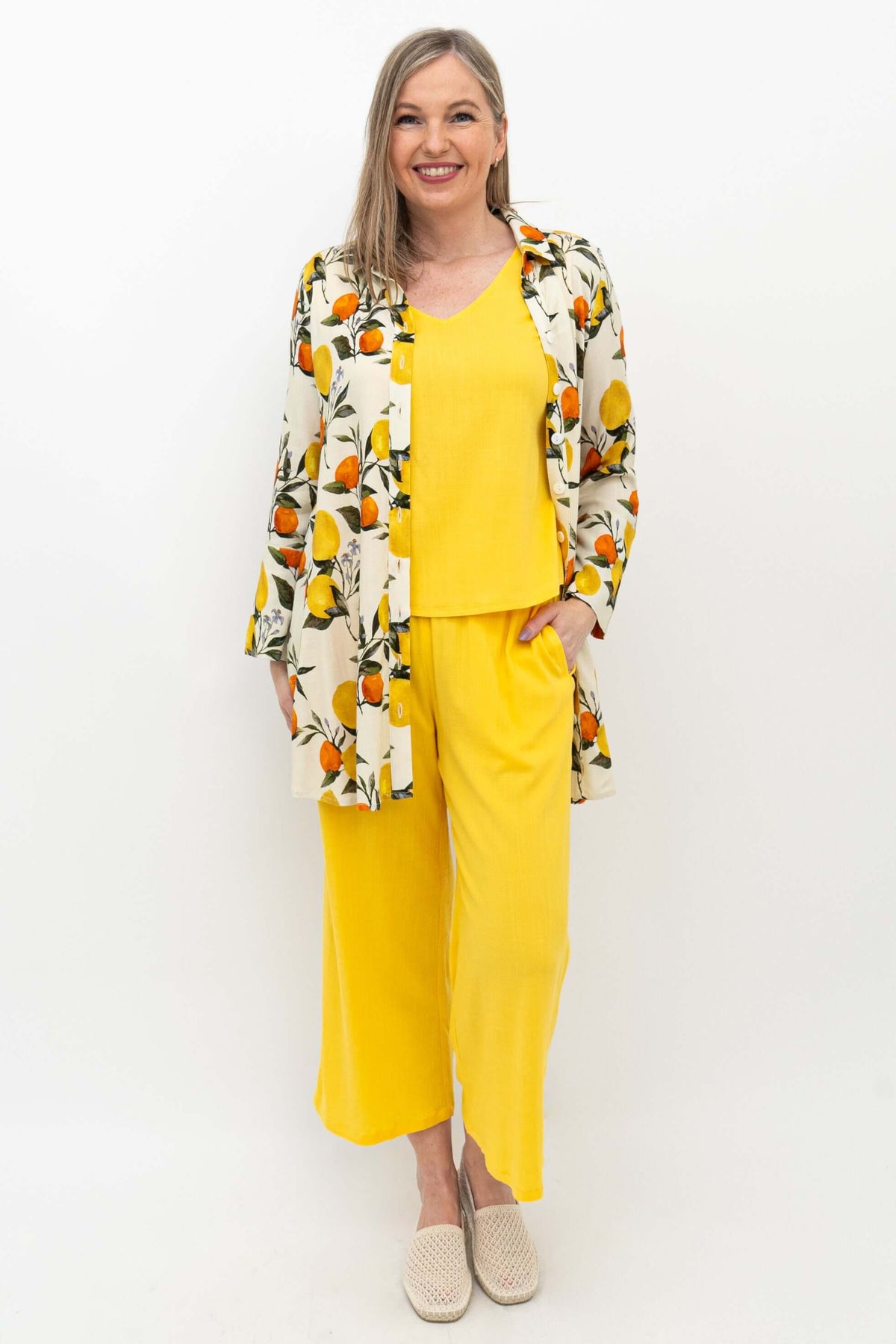 Woman wearing yellow capri pants, a matching top, and a patterned lemon print shirt