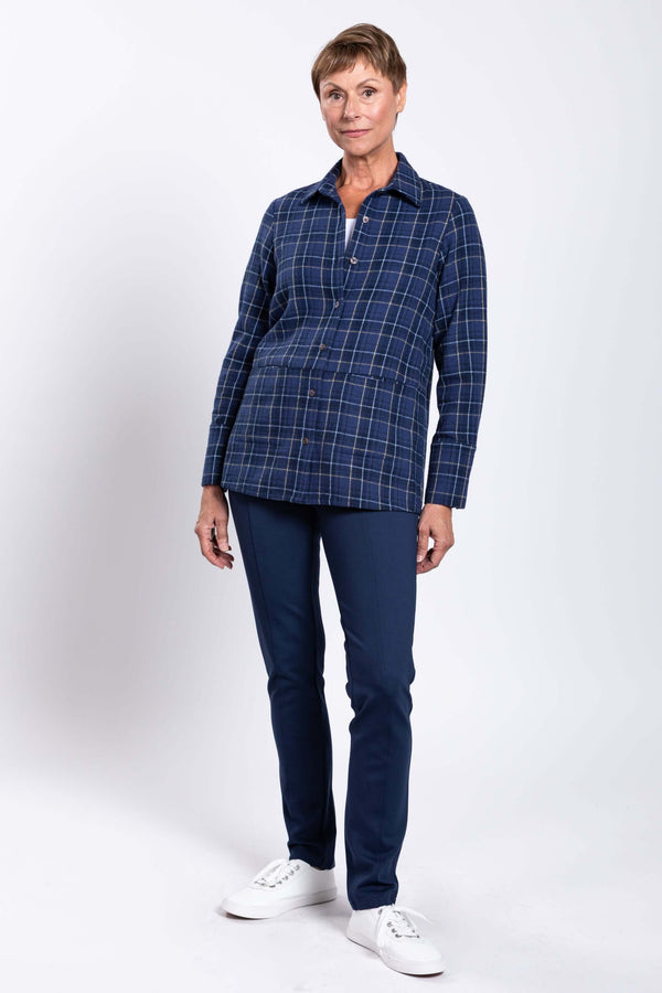 Full-body view of a woman in a blue plaid cotton jacket and navy pants